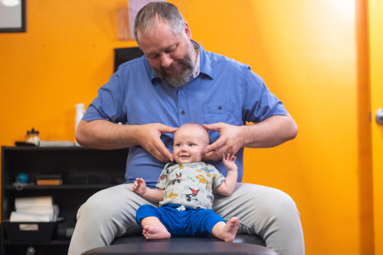 Dr. Matthew Roller holding an infant during a visit at Kids Only Chiropractic in Bluffdale, Utah